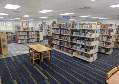 Shelving in the children's area of the library with tables and chairs